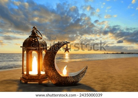 Shiny golden crescent moon with star lantern and arabic lantern on sea beach at beautiful sunset sky with cloud, Ramadan kareem background Royalty-Free Stock Photo #2435000339