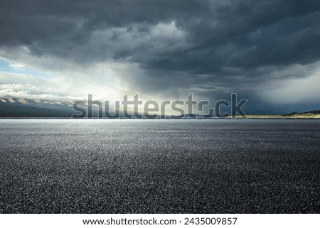 Asphalt road and mountains with dark clouds before heavy rain