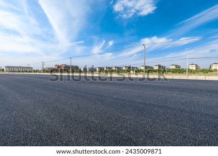 Rural asphalt road and residential area buildings under blue sky