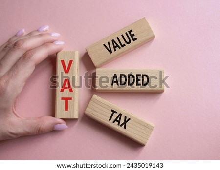 VAT - Value Added Tax symbol. Wooden cubes with word VAT. Businessman hand. Beautiful pink background. Business and Value Added Tax concept. Copy space.