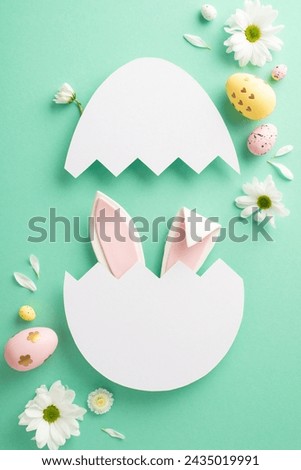 Easter sweetness theme. Overhead vertical photo of delightful bunny ears peeking through a broken egg shell, painted eggs, and chamomile buds on a teal backdrop, designated space for text or ads