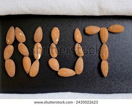 Nut lettering sign of almonds on black background. Healthy Eating Concept.