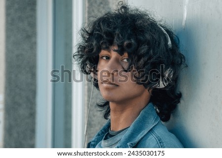 relaxed young afro man listening to music with headphones on the street