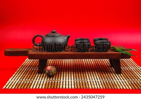 Black teapot and cups with bamboo leaves on a tray. Traditional tea ceremony.