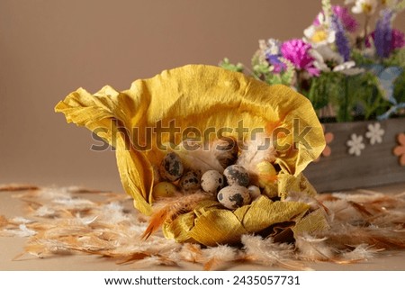 Crepe paper nest with easter eggs, feathers, and spring flowers on a beige background. Focus on a foreground.