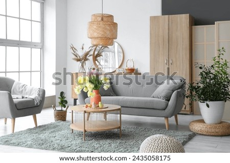 Interior of modern living room with flowers, Easter eggs and porcelain quails on coffee table Royalty-Free Stock Photo #2435058175