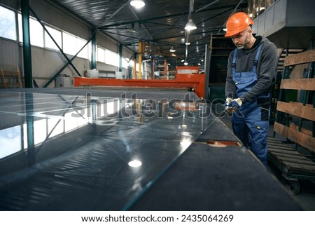 Worker cuts glass for a double-glazed window Royalty-Free Stock Photo #2435064269