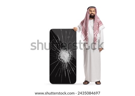 Saudi arab man in ethnic clothes leaning on a mobile phone with cracked screen isolated on white background