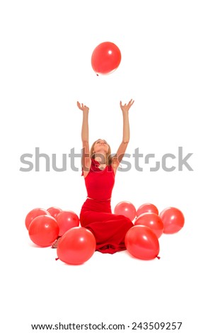 young woman plays with red balloons on white background