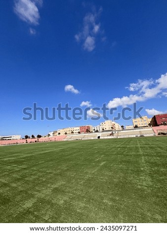 The picture of the football field is his houses and the weather is sunny and beautiful