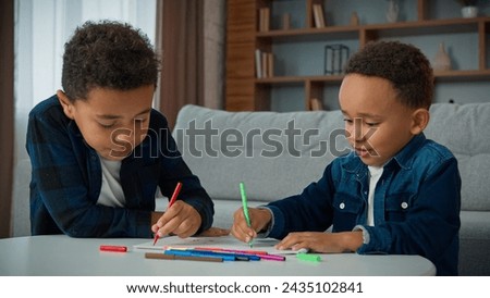 Two ethnic African American boys kids enjoy hobby art at home homework draw schoolboys brothers pupils siblings children drawing with colorful markers create picture with colored felt-tip pens paint