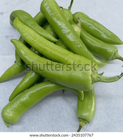 Long green Chili are curved to straight pods, averaging 7 to 15 centimeters in length. The skin is waxy, glossy, and smoot Royalty-Free Stock Photo #2435107767