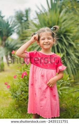 Girl in a pink dress with flowers. Little girl with palm trees.