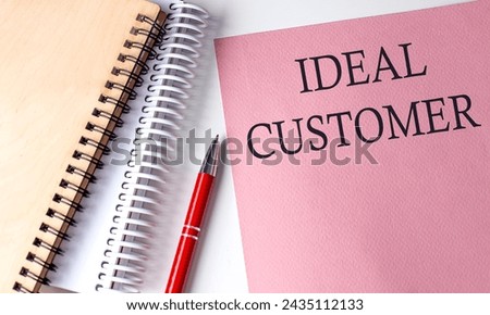 IDEAL CUSTOMER word on pink paper with office tools on white background