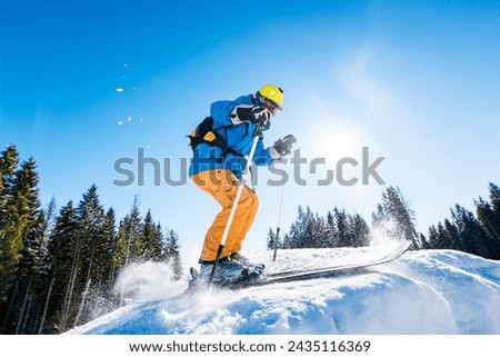 Professional male skier skiing on fresh snow in the mountains on a sunny beautiful day extreme fun happiness activity lifestyle concept Royalty-Free Stock Photo #2435116369