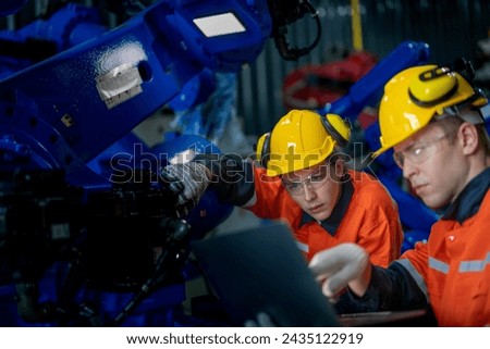 Business engineers meet and check control heavy machine robot arm. Diverse Team of Industrial Robotics Engineers Gathered Around machine. Professional Machinery Operator Use Industrial Digital Tablet. Royalty-Free Stock Photo #2435122919