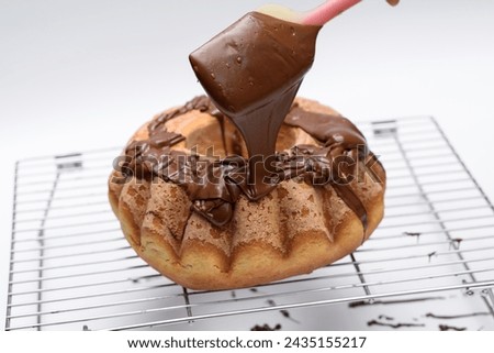 Warm Easter cake covered with chocolate stands on a metal grid, icing on a yeast cake Royalty-Free Stock Photo #2435155217