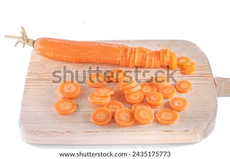 A carrot cut lengthwise and sliced, pieces scattered on a wooden chopping board. Isolated on a white background studio shot high quality image close-up macrophotograph. Oblique overhead view. Royalty-Free Stock Photo #2435175773