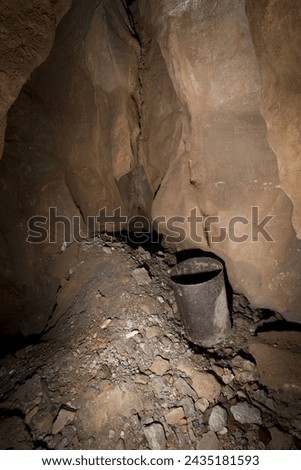 An old rusty bucket at the bottom of a karst abyss. Royalty-Free Stock Photo #2435181593
