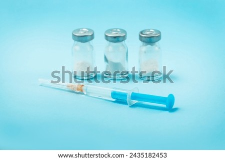 Syringe and needle with glass medical ampoule vials for injection. Medicine is dry white drug penicillin powder or liquid with of aqueous solution in ampulla Royalty-Free Stock Photo #2435182453