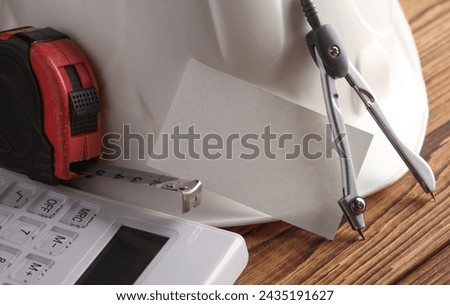 Engineer's tools and white blank business card on wooden boards.