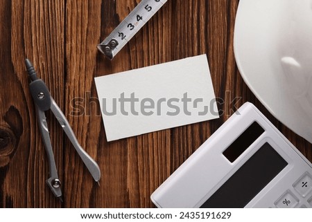 Engineer's tools and white blank business card on wooden boards. Top view