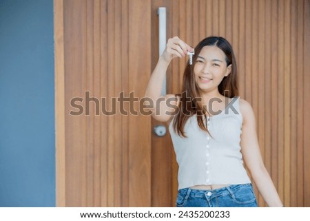 Focus at key with blur Young Asian woman holding it with smile of gladness and happiness, got new home, buy new home concept.