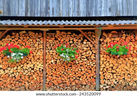 Chopped wood stack decorated with red and white flower pots, Tirol, Austria