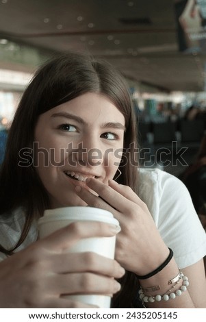 Young woman drinking coffee and smiling during a stopover at an international airport