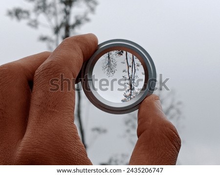 Asian person's hand holding a lens on a beautiful natural background
