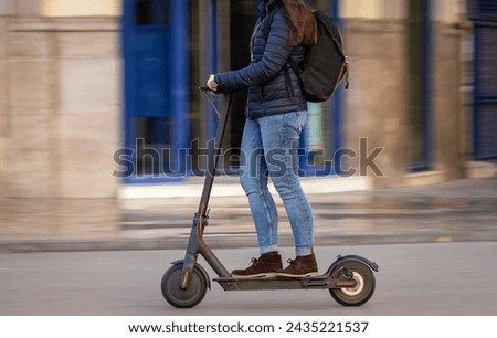 Woman pushing e-scooter in the city,  Ecological transport. Sweeping motion. Royalty-Free Stock Photo #2435221537