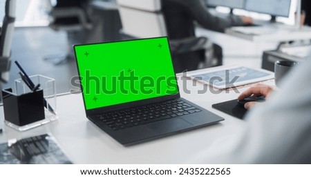 Successful Caucasian Businessman Sitting at Desk Working on Green Screen Laptop Computer in Office. Anonymous Businessperson using Chroma Key Display. Stylish Bright Workplace. Over Shoulder Close Up. Royalty-Free Stock Photo #2435222565