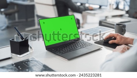 Successful Caucasian Businessman Sitting at Desk Working on Green Screen Laptop Computer in Office. Anonymous Businessperson using Chroma Key Display. Stylish Bright Workplace. Over Shoulder Close-up. Royalty-Free Stock Photo #2435223281
