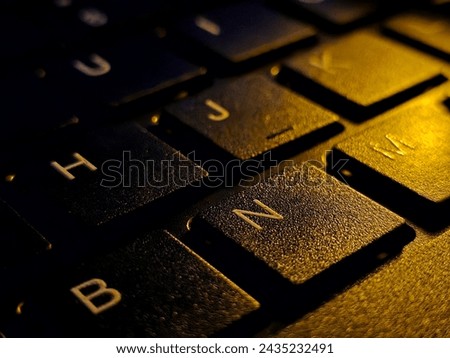 Close-up of computer keyboard with N alphabet focused. Typing keyboard close-up conceptual picture in dark.