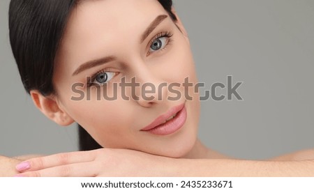 beautiful, young model rests her head on her hand, lying down and looking at the camera. The concept of healthy skin and female beauty, cosmetology services.