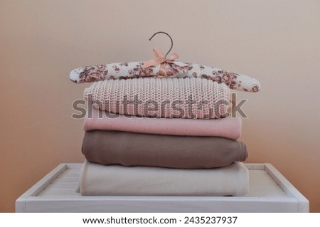 Stack of warm wool and cotton sweaters and hanger on light white wooden table. Space for text