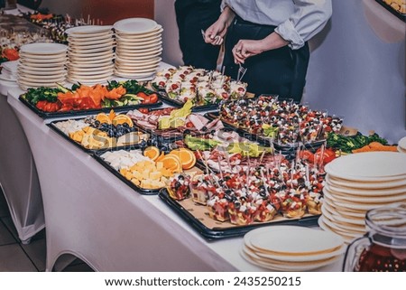 This image depicts an appetizing buffet spread with a variety of dishes beautifully displayed. To the left, there are stacks of clean, white plates ready for guests to use.