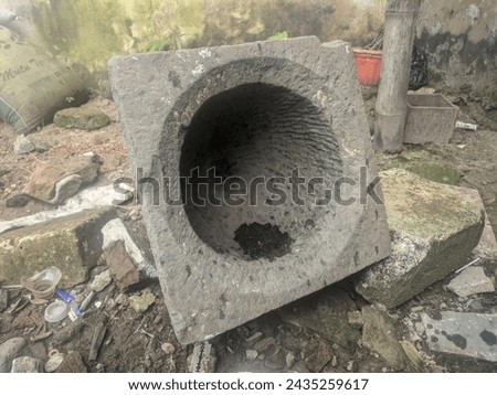 Unused ancient stone mortar lying on the ground, photo of ancient object, traditional equipment for pounding rice