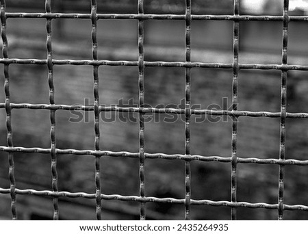 Iron bars separate the prison from the wall in the background with very dark tones for a dramatic black and white effect Royalty-Free Stock Photo #2435264935