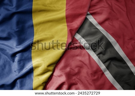 big waving national colorful flag of trinidad and tobago and national flag of romania . macro