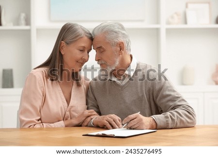 Senior couple signing Last Will and Testament indoors