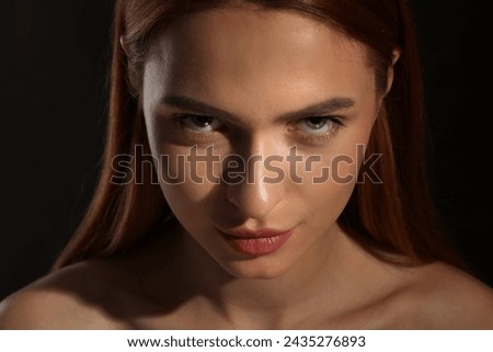 Evil eye. Young woman with scary eyes on black background, closeup