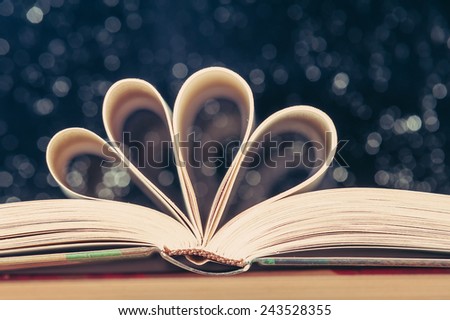 Open book on wooden table with bokeh effect in the backgroun, vingate edition