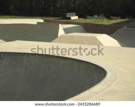 architectural skating park structure with bowls and slanted tracks paveways        Royalty-Free Stock Photo #2435286689