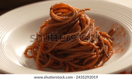 Pasta with Tomato Sauce on plate. Step of Recipe Fried Assassin's Spaghetti Cooking. Close-up, shallow dof.