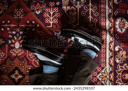 Product concept photo of classic two-tone wingtip brogue shoes made of genuine leather worn by a man with trousers on the classic Turkish red carpet.