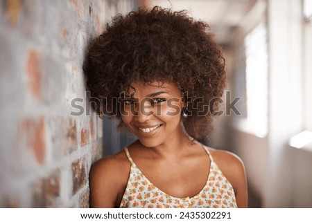 Portrait, smile and woman by brick wall at university for confidence, education or learning in corridor alone. Face, happy student and girl in hallway of college for profile picture in South Africa