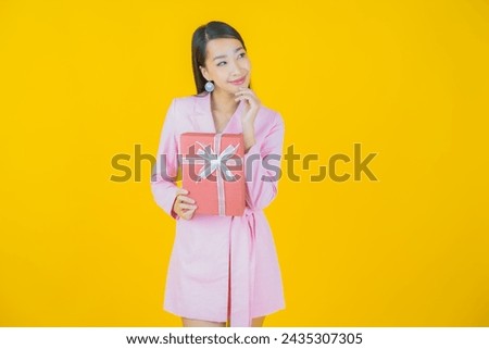 Portrait beautiful young asian woman smile with red gift box on color background