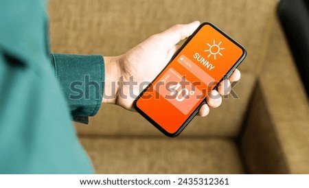  Hand holding smartphone with weather hot sunny day on screen and sunrise on midday at dry forest background. High Temperature Weather show on Mobile Screen on Hot Sunny Day. concept global warming Royalty-Free Stock Photo #2435312361