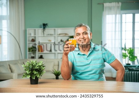 Indian mid age handsome man drinking fresh juice in a glass Royalty-Free Stock Photo #2435329755